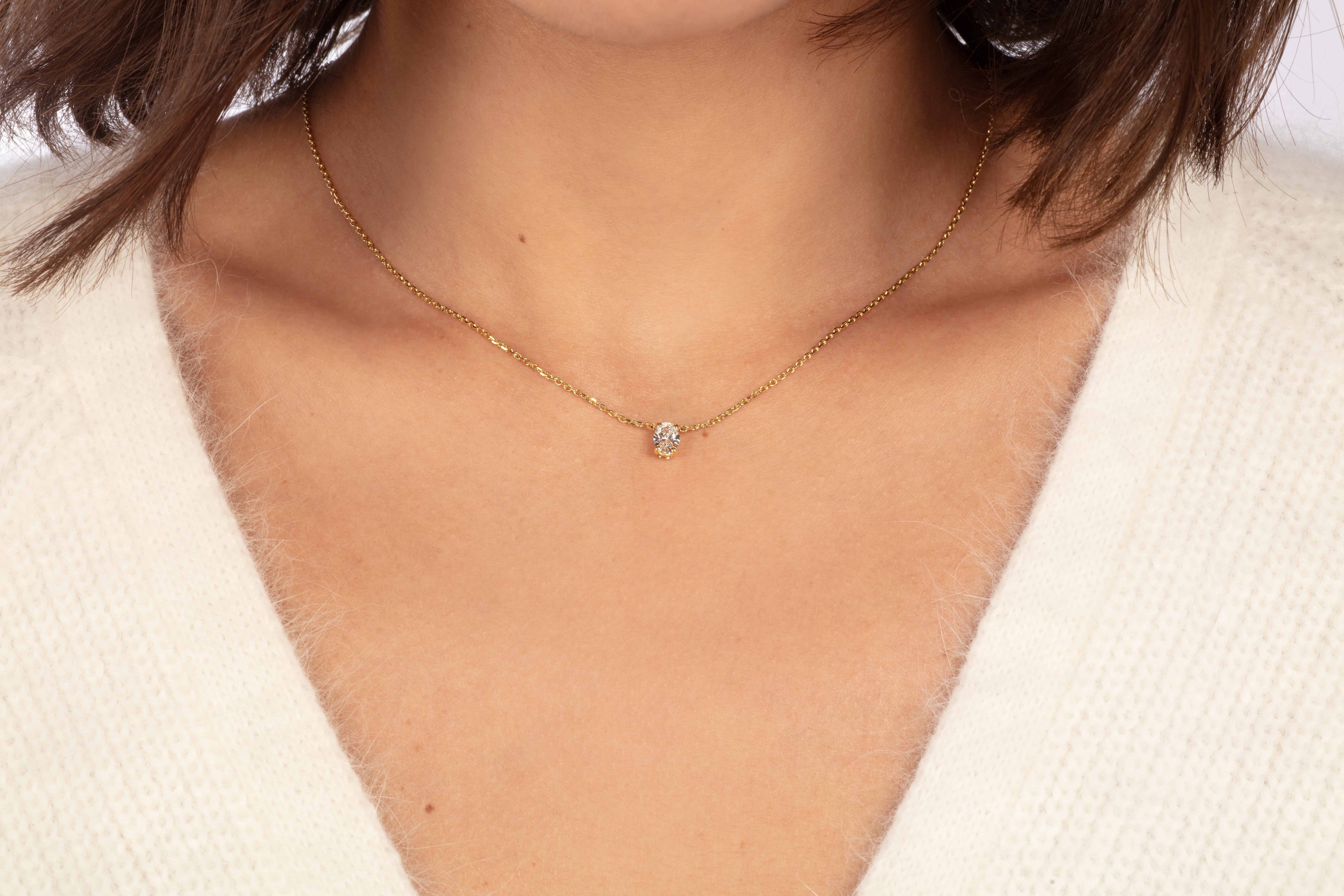 Eine Nahaufnahme zeigt jemanden, der die Halskette ERATO ROSÉGOLD von Atelier Sofia trägt. Die Person trägt einen weichen, weißen Flauschpullover, wobei vor einem neutralen Hintergrund nur der Hals und ein Stück der Schulter sichtbar sind.