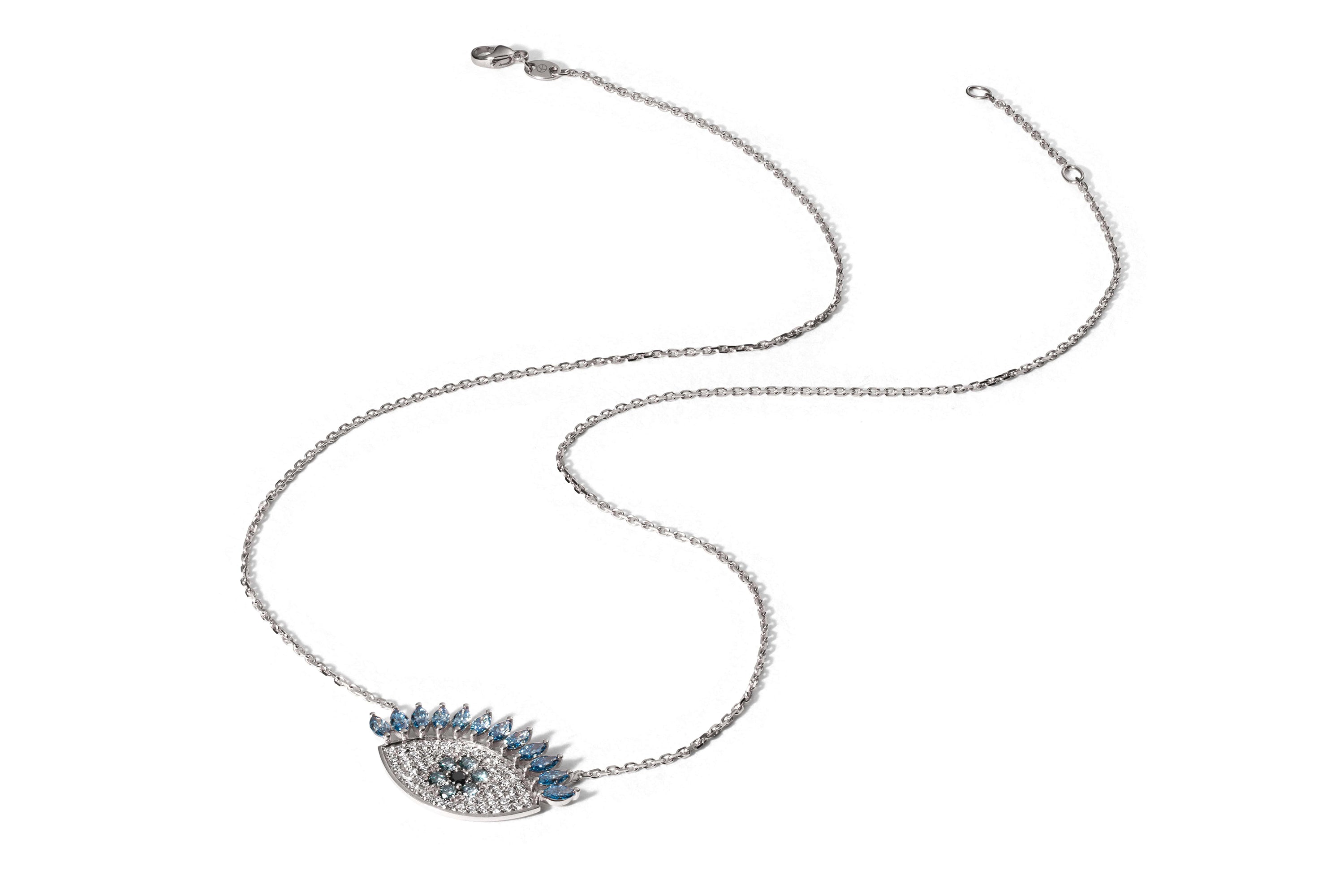 Die KLIO WEIßGOLD von Atelier Sofia ist eine Halskette aus 18 Karat Weißgold mit einer zarten Kette. Sie verfügt über einen augenförmigen Anhänger, der mit im Labor gezüchtetem Glanz, blauen Wimpern und einem zentralen türkisfarbenen Detail für einen anspruchsvollen Look geschmückt ist.
